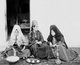 Palestine: Three Palestinian women drinking coffee and smoking a narghile water pipe, c. 1920